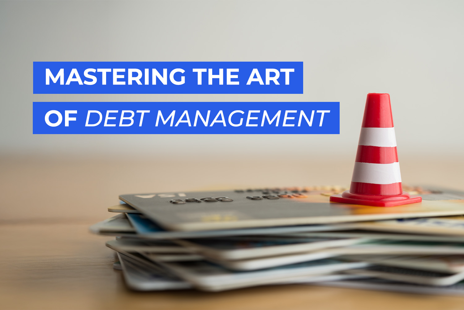 A stack of credit cards on a wooden surface with a small red-and-white caution cone, symbolizing the concept of debt management on 3elm El geib